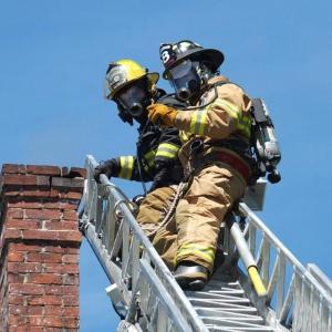 Boothbay firefighter David Steinmetz, top, and Boothbay Harbor firefighter Dan Gagnon stand by on the ladder truck during a minor chimney fire at Linekin Bay Bed & Breakfast, May 15. RYAN LEIGHTON/Boothbay Register