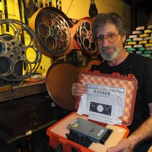 Jason Sheckley holds a new digital movie “The Great Gatsby,” while posing amongst old film equipment. The theater underwent a digital conversion on May 8. RYAN LEIGHTON/Boothbay Register
