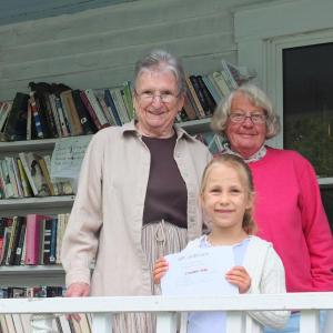  Friends President Jean Dube, left, and volunteer Carolyn Mayne, right, congratulate Hattie Moss, foreground, who won the Used Bookstore’s dove naming contest and a $25 gift certificate to the bookstore. Moss named momma bird “Booksen.”  SUE MELLO/BoothbayRegister.