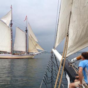 Ron Adolf, a passenger on the "Lewis R. French," hangs his feet over the bow as he watches the Heritage sail into Boothbay Harbor. RYAN LEIGHTON/Boothbay Register
