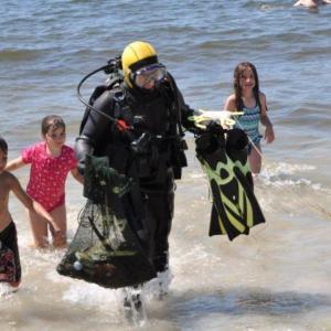 Young beach-goers swarm around Brian Boone as he returns with a bag full of sea creatures and other found items. From a 45-minute dive, Boone culled squid eggs, a juvenile lobster, several hermit crabs, a golf ball, a quahog and one feisty rock crab from the waters off Pemaquid Beach. BEN BULKELEY/Boothbay Register Young beach-goers swarm around Brian Boone as he returns with a bag full of sea creatures and other found items. From a 45-minute dive, Boone culled squid eggs, a juvenile lobster, several hermit crabs, a golf ball, a quahog and one feisty rock crab from the waters off Pemaquid Beach. BEN BULKELEY/Boothbay Register