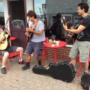 Outside of Red Cup Coffeehouse, owner/musician Paul Johnson (left) jams with jazz guitar legends Frank Vignola and Vinny Raniolo. JOE GELARDEN/Boothbay Register