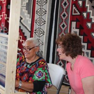 Jennie Slick, Master Navajo Weaver, demonstrates a technique during a workshop as student Fran Roggen looks on. Courtesy of Mary Walker