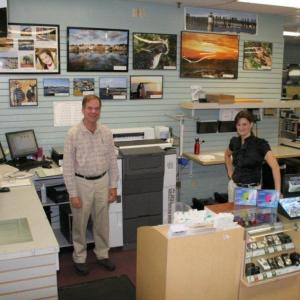 Conall O’Brien, left, and Leisha MacDougall stand in the photo processing area at Video Loft. The new, all-digital photo processing equipment speeds up delivery and photographs are sharper than when the business used chemicals to print photographs. KEVIN BURNHAM/Boothbay Register