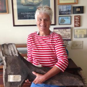 Sally Bullard holds a piece of the 'Charles W. Morgan,' originally removed during the first major restoration work performed between 1967 and 1970. The hanging knee timber is hand hewn oak. Hanging knees were vertical pieces cut from the natural section of oak where a limb grew out of the trunk and were fastened with large drift pins of iron or brass. LISA KRISTOFF/Boothbay Register
