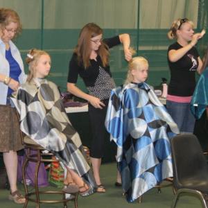 Three of the several volunteer hairdressers work on the locks of three young girls at the Set for Success event. KEVIN BURNHAM/Boothbay Register