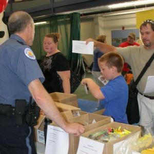 Boothbay Harbor Police Officer Larry Brown gets ready to help Dale Harmon and his son with the school supply list. KEVIN BURNHAM/Boothbay Register
