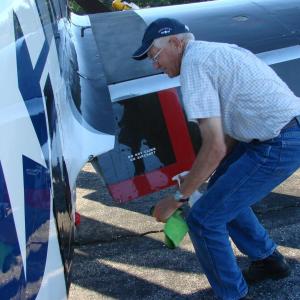 Dave Murphy, father of Texas Flying Legends Museum Warbirds pilot Mark Murphy works August 5 to  clean the plane his son would fly Tuesday. The elder Murphy owns the P-51. SUSAN JOHNS/Wiscasset Newspaper