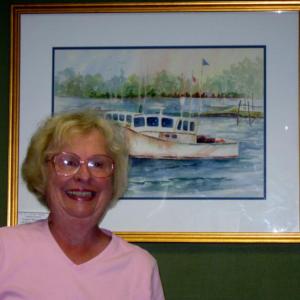 Virginia Forrest stands in front of her watercolor entitled "Boothbay Harbor Lobster Boats."
