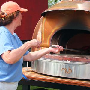 Shelly McLellan takes a wood-fired pizza out of her custom made oven. SUZI THAYER/Boothbay Register