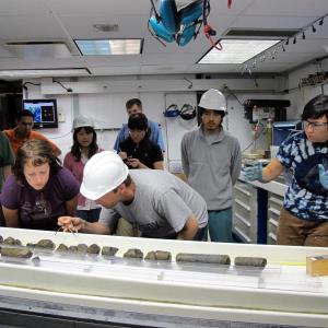 Dr. Beth Orcutt (front, second from left) of Bigelow Laboratory for Ocean Sciences examines oceanic crust samples with Dr. Wolfgang Bach of the University of Bremen, Germany, during IODP Expedition 336 to the Mid-Atlantic Ridge flank. Courtesy of Jennifer T. Magnusson