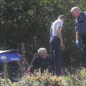 Officer Richard Mirabile talks with accident victim William Anderson sitting on the grass beside Route 96. KEVIN BURNHAM/Boothbay Register