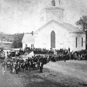 The 1848 Congregational Church on Townsend Avenue, as it appeared in 1880. Built by blacksmith-shipbuilder-hotel owner John Weymouth, the original roof was not as sharp as the present one, which was added in 1881. Having been in the upper part of the church, I know the older, massive, skeletal roof timbers are still in place. The 1880 crowd is on hand for Memorial Day. No doubt Charley's funeral 17 years earlier brought out a crowd many times the size of the 1880 one. Courtesy of the Boothbay Region Historical Society church