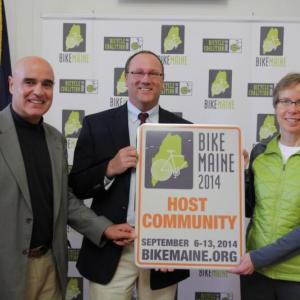 Boothbay Harbor Town Manager Tom Woodin, center, accepts a BikeMaine street sign from BikeMaine board member Mark Ishkanian and Ride Director Kim True in Portland on February 4. Boothbay Harbor is one of six Maine communities that bicyclists will visit next September. Boothbay Harbor is the only community where cyclists will stay for two nights. Courtesy of BikeMaine Photo of Tom Woodin