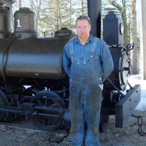 BRIAN FANSLAU of Alna stands in front of one the steam engines at the Boothbay Railway Village that is being made ready for the summer. SUZI THAYER/Boothbay Register