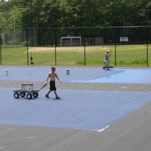 Workers with Maine Tennis and Track paint the tennis courts at Boothbay Region High School on Monday, June 30. KEVIN BURNHAM/Boothbay Register