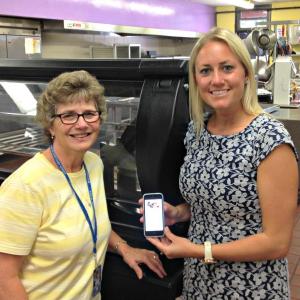Food Services Director Darlene French, left, and Caroline Jones, account manager and dietitian at Nutrislice in the BRES school cafeteria. Jones is holding her phone with the Nutrislice app. KATRINA CLARK/Boothbay Register