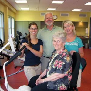 Miriam Wade sits on a new exercise bike designed specifically for people with Parkinson’s that she donated to the St. Andrews Campus of LincolnHealth. Standing behind Miriam are Occupational Therapist Lisa Castonguay, left, who offers LSVT BIG therapy to help people with Parkinson’s move better, Speech Therapist Jennifer Bryce, who offers LSVT LOUD therapy to help people with Parkinson’s overcome speech problems associated with the disorder, and Physical Therapist Jim Stevens, Site Supervisor of the St. Andrews Wellness Department. Courtesy of LincolnHealth