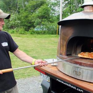ERIC CORNELL takes a finished pizza out of the wood-fired copper oven used at CRUST. SUZI THAYER/Boothbay Register