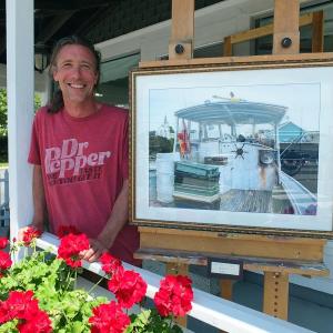 NATHAN CAMPBELL stands next to one of his favorite paintings, on the deck of his new Eastside Gallery at 26 Atlantic Avenue in Boothbay Harbor. SUZI THAYER/Boothbay Register