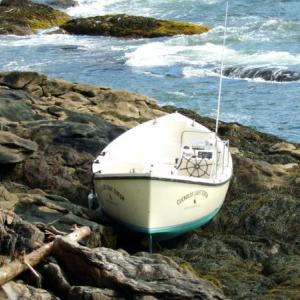 THE 26-FOOT WHALEBOAT, recently restored to transport visitors to the new Inn at Cuckolds Light Station, came to rest on ledges at Horn Cove on Southport Wednesday night, after storm surges caused it to break loose from the Cuckolds. SUZI THAYER/Boothbay Register