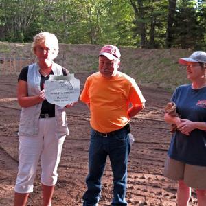 Sgt. Robert Streng's close friends, Cathy and Dana Hodgdon, left and center, receive a plaque in the shape of Sgt. Streng's badge from Tammy Steinmetz, right, on behalf of the association, for his generosity and dedication to the club. The plaque will hang on the pavilion wall in his honor. Courtesy of Stephen Rubicam