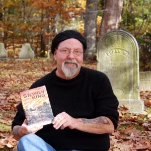 NEAR BOOTHBAY HARBOR’S Pear Street Cemetery on Oct. 30, Glenn Chadbourne holds a just-published collector’s edition of Stephen King’s “Carrie,” illustrated by Chadbourne. SUZI THAYER/Boothbay Register