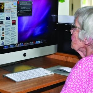 An Independence At Home senior reading online. Courtesy of the ElderCare Network