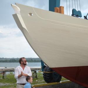 Noah Barnes and his son, Oscar, stand at the bow of the Ladona on the St. George River before the soft relaunching of the historic vessel. (Photo by Lynda Clancy)
