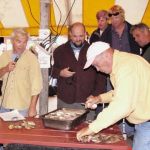 The scene was as serious as it gets at the 2010 Pemaquid Oyster Festival Maine Champion Oyster Shucking Contest as the contestants’ efforts are carefully regarded by judges behind them while emcee Larry Sidelinger, left, calls the action. Courtesy of Greg Latimer