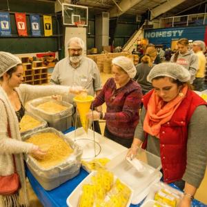 Tom Dewey and pastor Sarah Foulger of Boothbay Harbor's Congregational Church (center left and center right) on the assembly line at Sunday's "End Hunger in New England" event, a joint venture between the Boothbay Harbor Rotary and Damariscotta-Newcastle Rotary clubs to package food packets for needy area families. Courtesy of Steve Demeranville