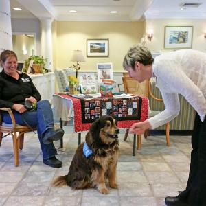 Village Resident Services Supervisor Barbara Marr makes quick friends with “Marlee,” who was an official guest at the animal shelter luncheon and fundraiser. Courtesy photo
