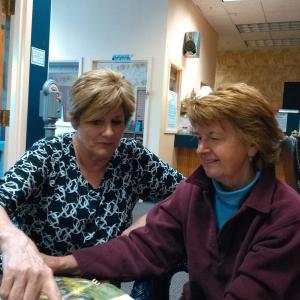 Jane Good and Gail MacPhee look through national publications showing gardens that have received MacPhee’s special touch. JANE CARPENTER/ Boothbay Register