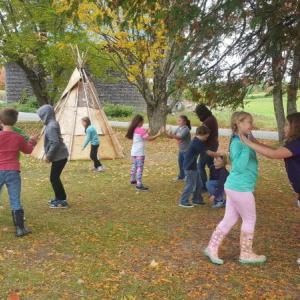Woolwich Central School students play traditional Wabanaki games in front of the DRA birch bark wigwam, which was constructed with student involvement. Courtesy photo