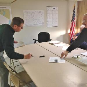 Edgecomb resident John Ross shows Selectman Ted Hugger the current Edgecomb Eddy School newsletter during the April 24 meeting. Ross recommended town officials post each newsletter on the municipal website. BILL PEARSON/Boothbay Register