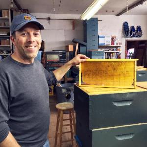 Tim Forrester holds a beehive frame in his Woolwich workshop. SUZI THAYER/Boothbay Register