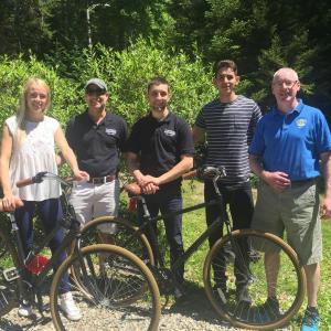 Summer workers from Lithuania and other parts of Eastern Europe, from left, Indre, Mindaugars, Mark, and Radu, receive their bikes from Rotarian Rick Elder. Courtesy of Cornelia Seybold