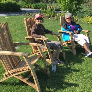 The new chairs built from barrels by Boothbay Region High School students for Coastal Maine Botanical Gardens get tested by a couple of women on a recent day. Courtesy of Kris Folsom/CMBG