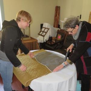 Katie Likens, left, a graduate student at the University of Rhode Island, and JoAnn Stabb, professor emerita, University of California at Davis, use a special vacuum to clean one of Lincoln County Historical Association’s 18th century quilts. The soft mesh screen prevents fibers from breaking. Courtesy of Christine Hopf-Lovette