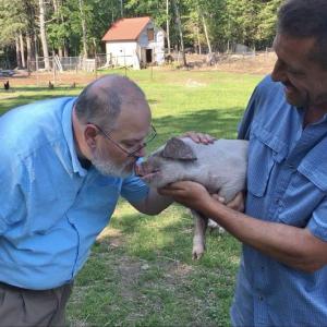 Boothbay Region Elementary School Principal Mark Tess kisses a two-day old piglet while the piglet’s owner, Seth Lewis, holds him. Courtesy of Lauren Brown/BRES