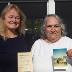 Barbara Belknap of Damariscotta, left, and Vice Regent Louise Brown hold an invitation and a photo of past tree dedications in Wiscasset from 1938 and 1996. Courtesy of Audrey Leeds Miller