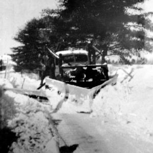 A truck owned by the former Ivan C. Shaw and Sons Construction of Woolwich appears stuck in the snow, its driver on the wing of the plow. The picture was taken near Walker Road possibly in the late 1940s or early 1950s. Courtesy of Jack A. Shaw and Sons Construction