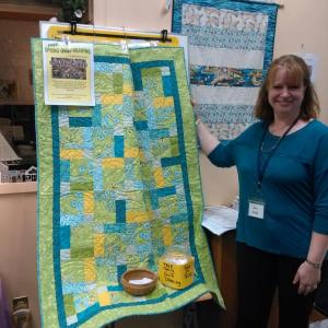 Community Center secretary Jen Field shows the beautiful quilt made by the Center’s “Just Sew” group for a May 15 drawing. JANE CARPENTER/Boothbay Register