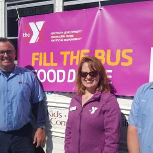 Robert Emerson from Dead River, Kate Borsig from the YMCA and Nick Greenleaf from Dead River stand outside the Y bus during the “Fill the Bus” food donation event. Courtesy of Fleet Davies
