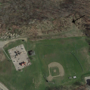 Pat Farrin and Tom Nickerson hope to draw some skilled volunteers to convert the piles of fill on the north side of Clifford Playground to usable fields. The area is shown between the dirt road and arrows. Courtesy of Google Earth
