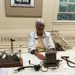 Jean Hawley sits at a table with examples of some of the interesting artifacts from the museum including a raisin seeder and a very early version of an electric toaster. Courtesy of Carole Zalucky
