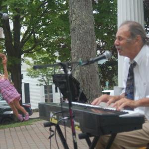 “Ragtime” Jack Radcliffe plays as Noa, 2, is swung by her dad Will Marbury of Baltimore. ART MAYERS/Boothbay Register