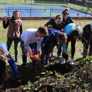 From left, Emerson Harris, Interact adviser Ingrid Merrill, Henry Drapeau, Rowan Kristan, Kylie Brown, Lexi Lane, Glory Blethen, and Linda Bonin of the Garden Club plant a hope garden. Courtesy of Jim Singer