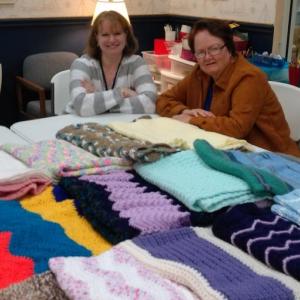 Community Center secretary Jen Field, left, and Carol Cragin, knitting group coordinator, admire lap blankets made by the center’s knitters and headed to hospice patients. JANE CARPENTER/Boothbay Register