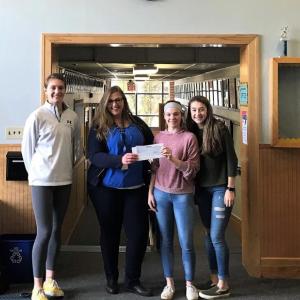 Kristen Lewis from Camden National Bank presents donation to Boothbay Region High School girls basketball players Faith Blethen, Ashley Abbott and Chloe Arsenault. Courtesy of Camden National Bank